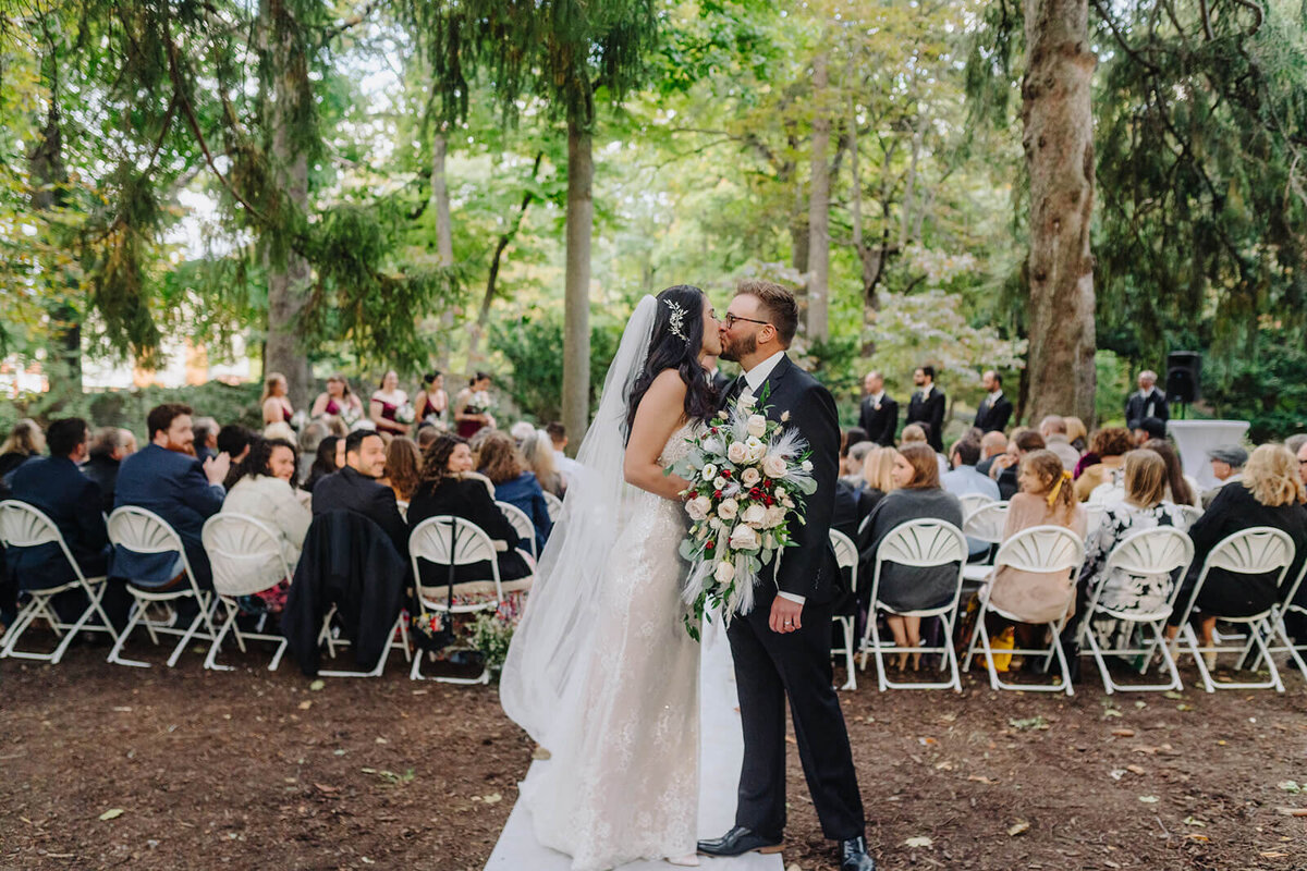 Bride and groom kissing in front of guests at Finger Lakes wedding, NY