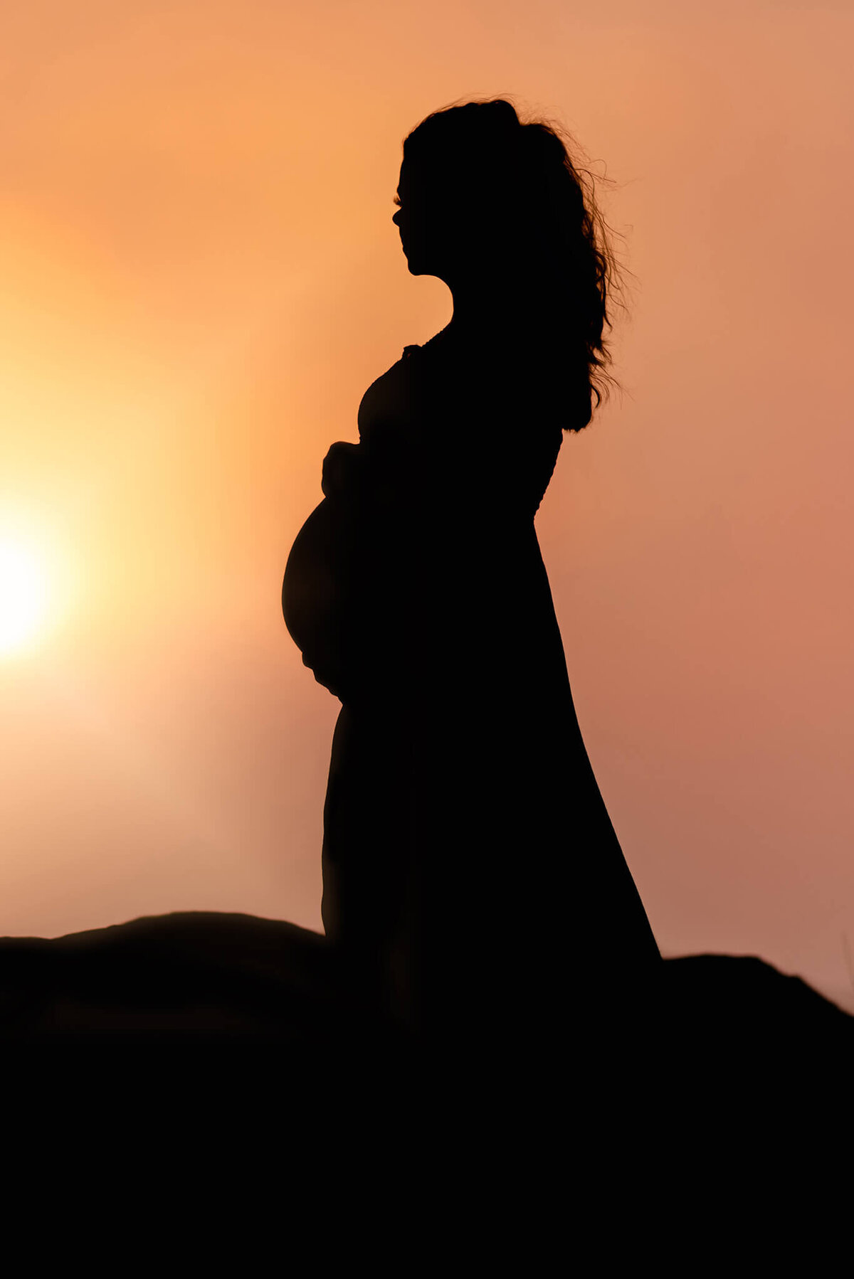 A dramatic sunset silhouette of a beautiful pregnant woman captured in Tobiano by Brittany Danielle