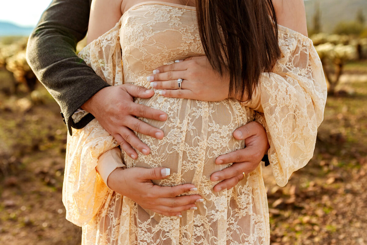 close up of a beautiful baby bump cradled by parents