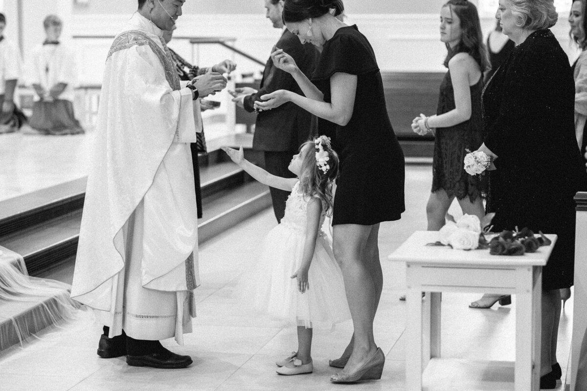 Child and mother receiving communion from a priest