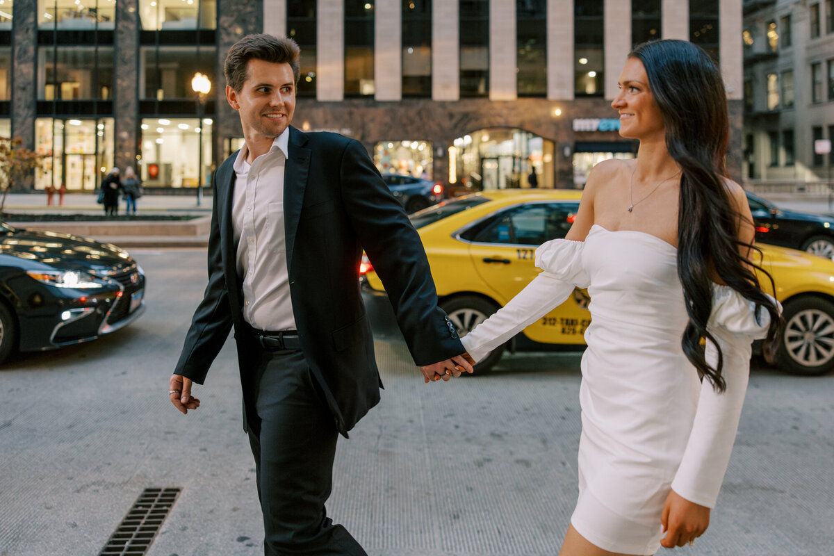 A couple embraces at dusk along Michigan Avenue and the Chicago River, with the city lights creating a romantic and timeless backdrop.