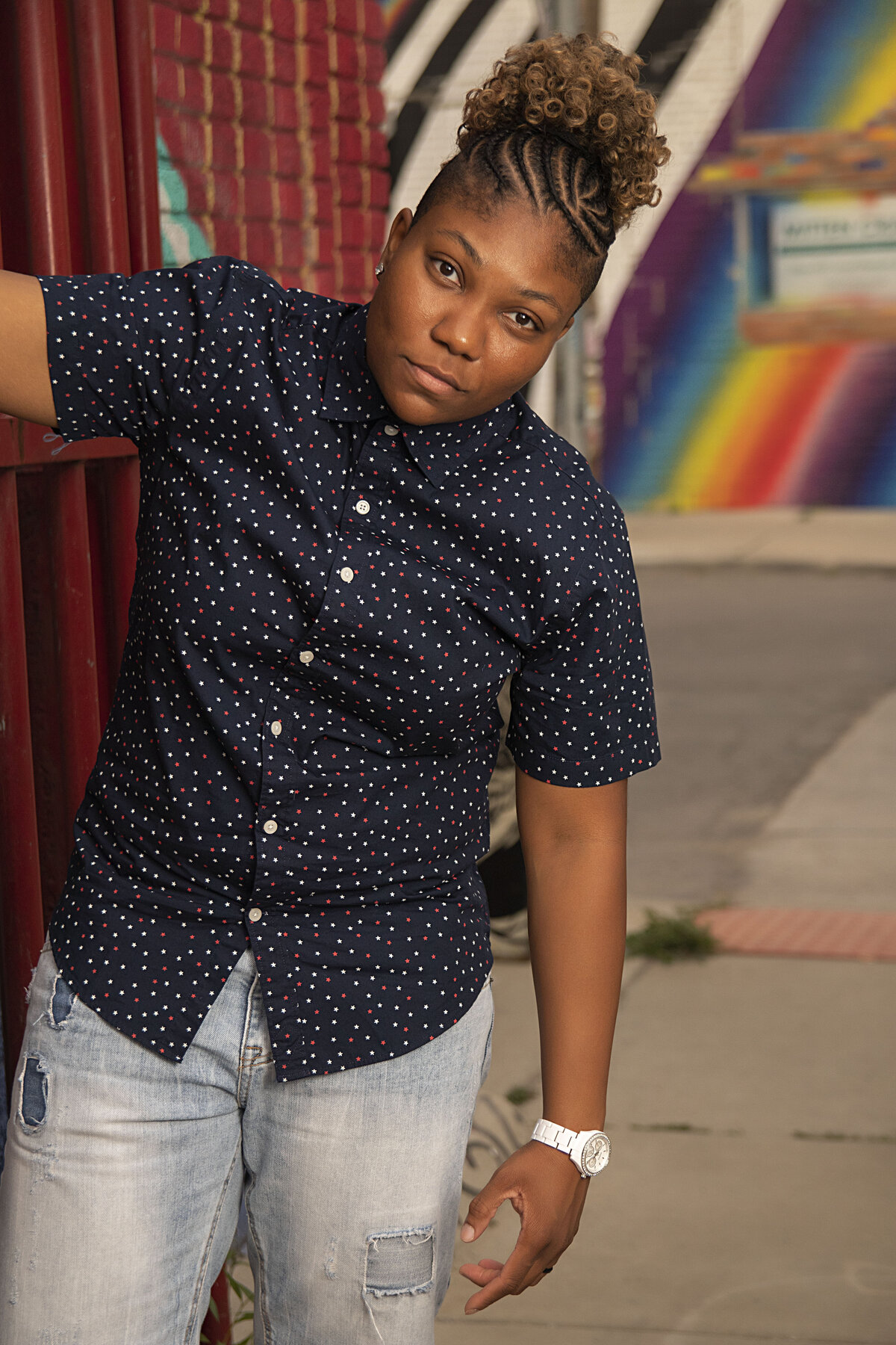 African American woman in blue button up top and blue jean shorts hanging from a doorwall