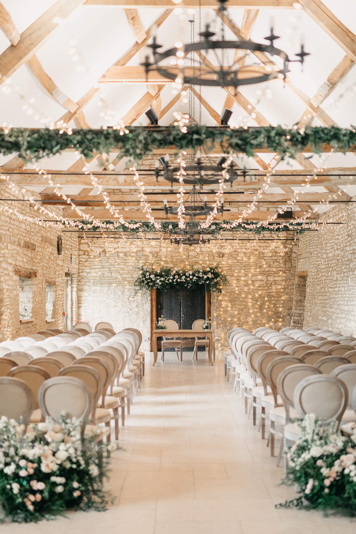 Light and airy wedding ceremony setup in Caswell House barn with fairy lights and elegant styling