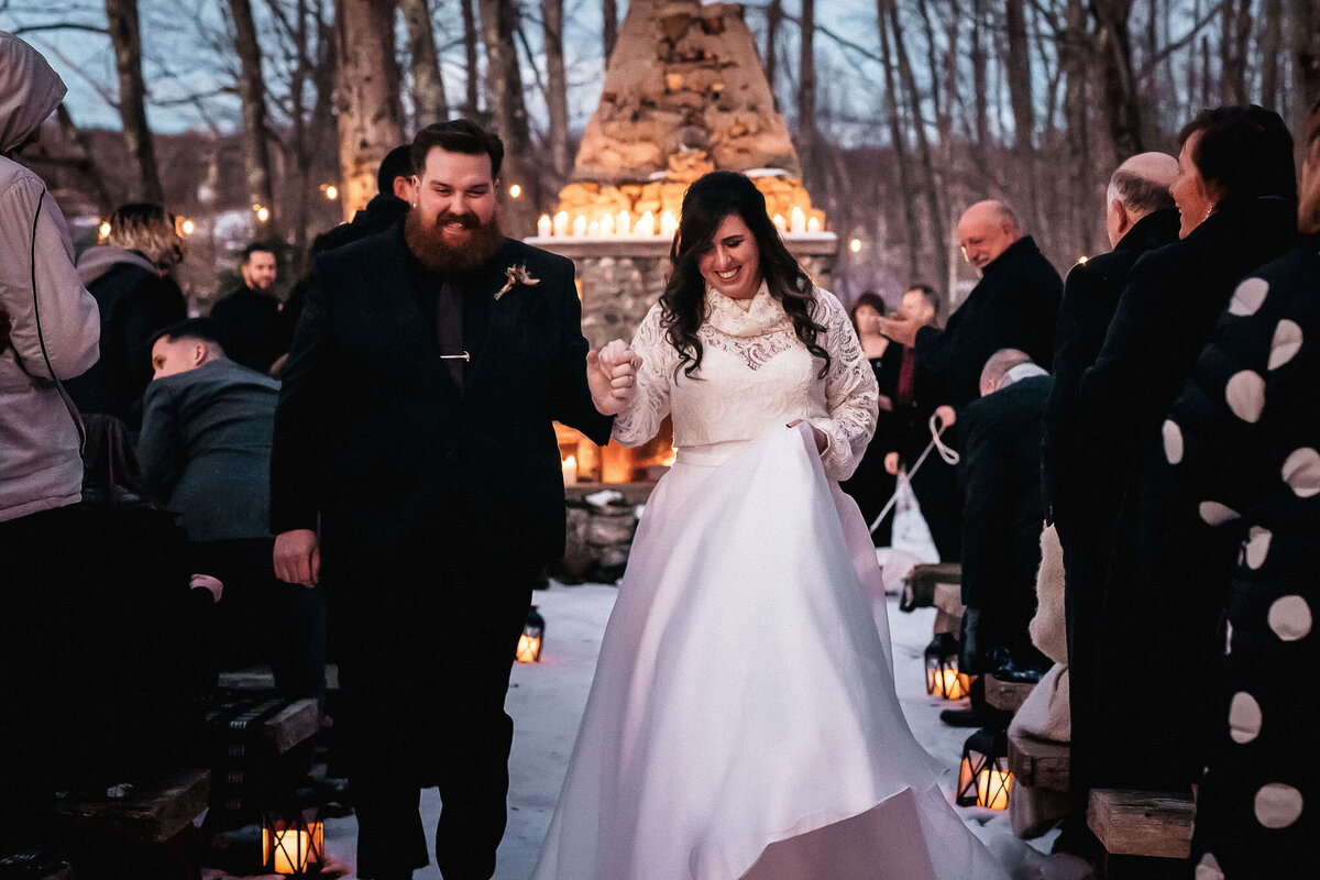 Bride and Groom exit down the aisle after beautiful candle lit wedding ceremony at Whitney's Inn in Jackson NH by Lisa Smith Photography