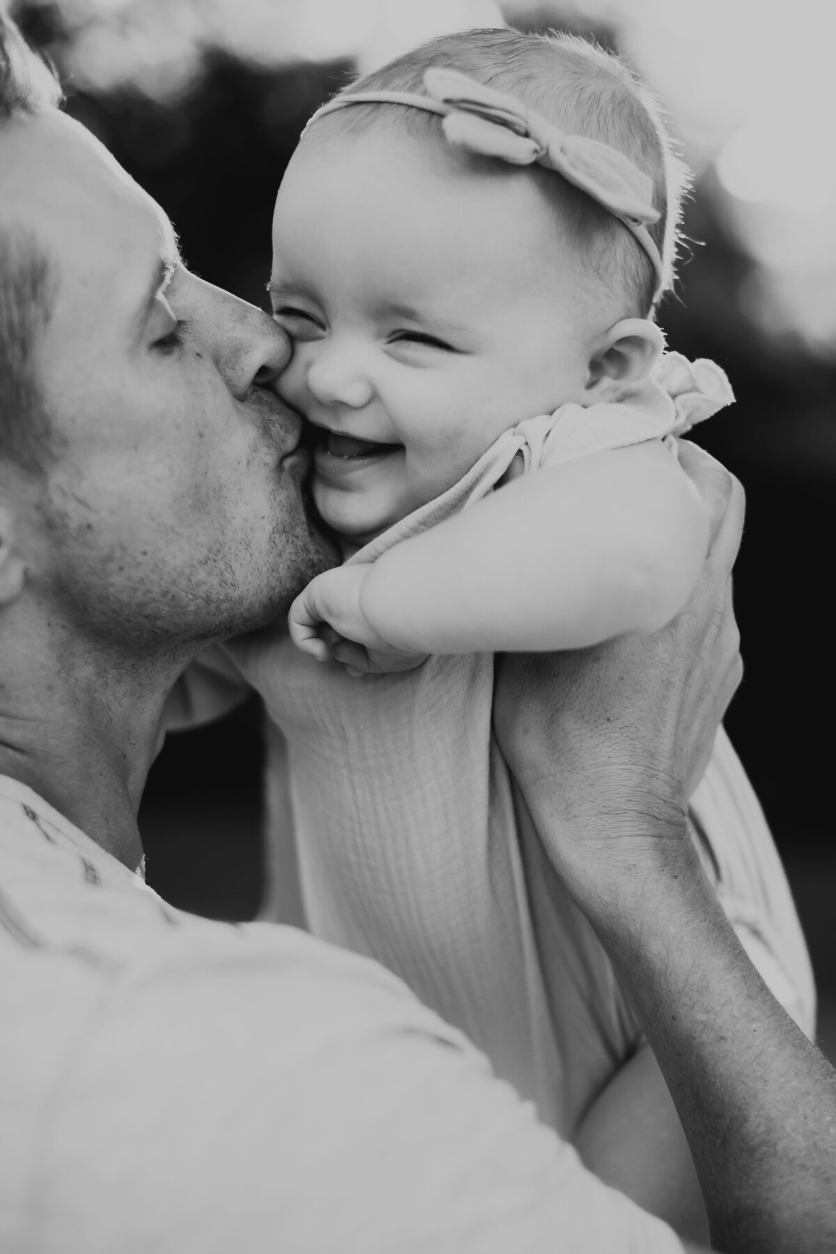 dad kissing laughing baby girl on the cheek