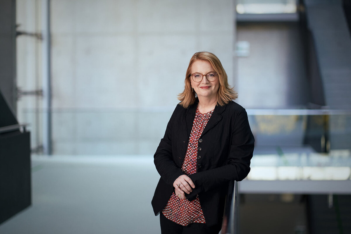 Freundliches Businessportrait einer Unternehmerin vor moderner Architektur – fotografiert von Atelier Schulte in Wien. Professionelle Businessfotografie für Unternehmen österreichweit.