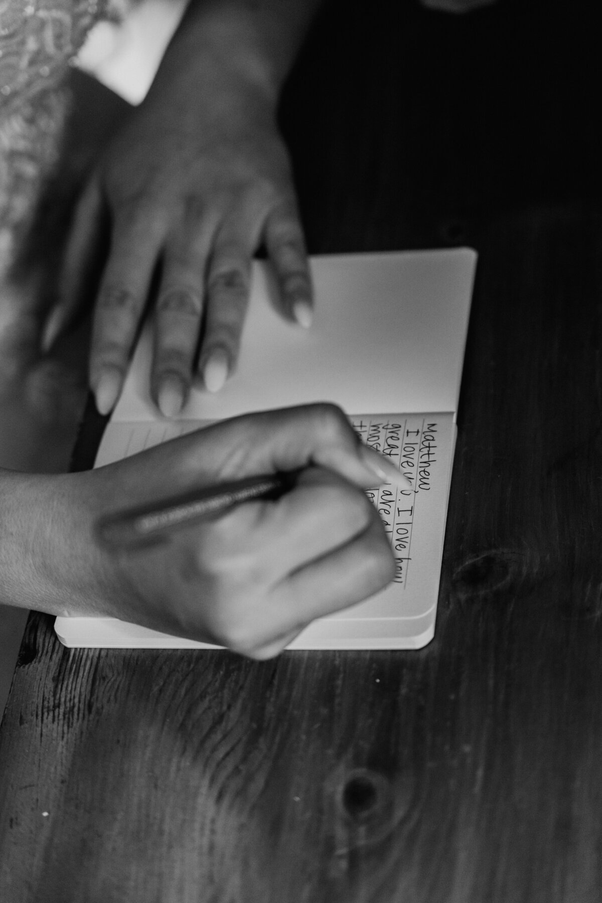 Close-up of bride’s hand writing vows in notebook