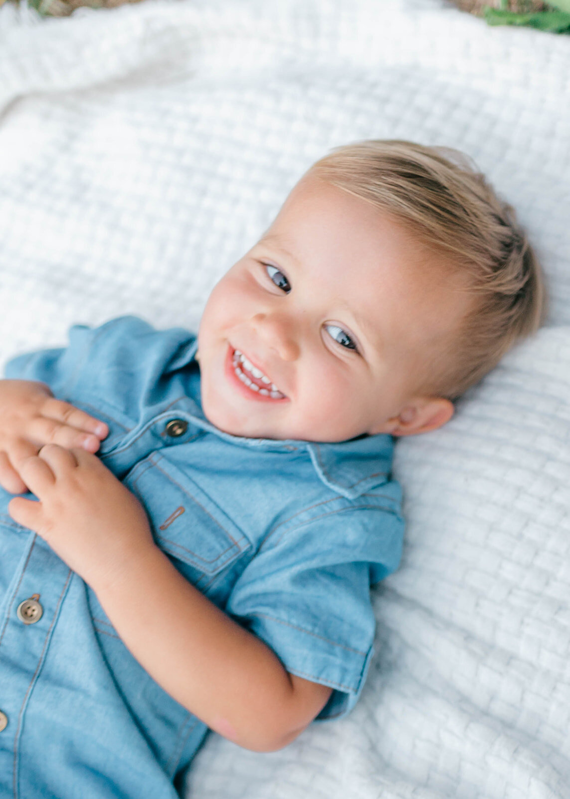 Toddler boy laying on blanket on grass