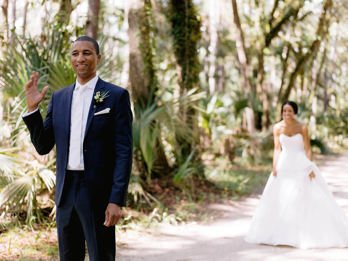 The bride is walking behind the groom, amongst nature in Montage at Palmetto Bluff. Destination wedding image by Jenny Fu Studio