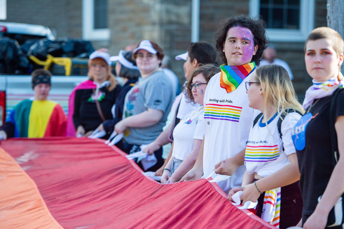 Ottawa event photography showing pride marches waving a red pride parachute. Captured by JEMMAN Photography COMMERCIAL