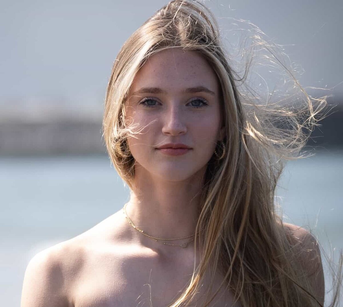 Headshot of a beautiful young woman at the beach with long flowing blonde hair blowing in the wind
