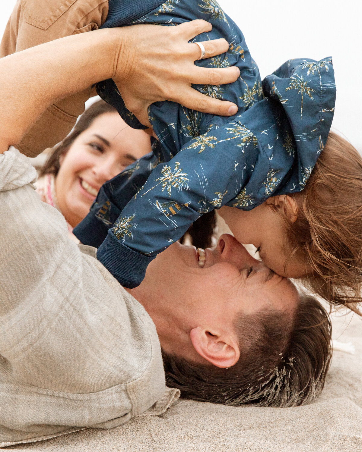 Dad throwing his baby above his head playfully, with mom laughing behind. Joyful and dynamic family photography in Portland and Nashville.