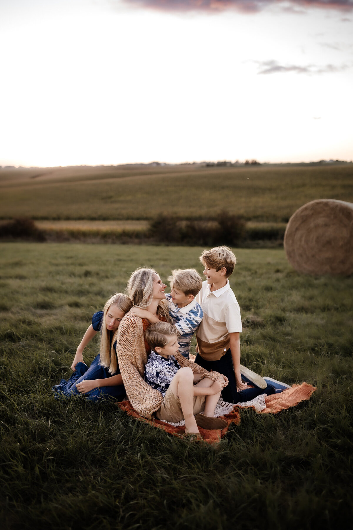 mom and children sitting on blanket by hay bales