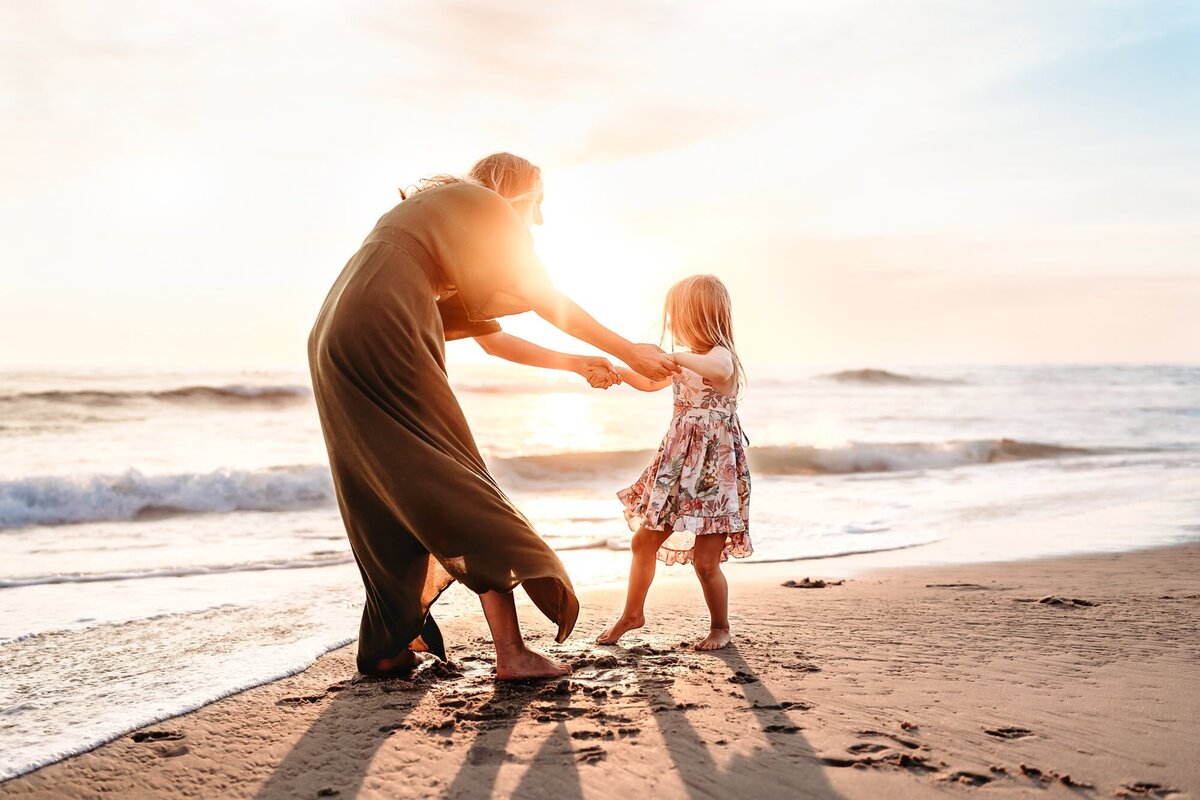 Mother playing with her young daughter on a La Jolla beach at sunset, captured by San Diego family photographer.