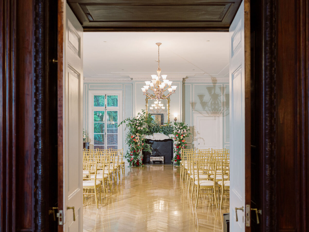Ceremony setup with gold chairs facing a floral arch
