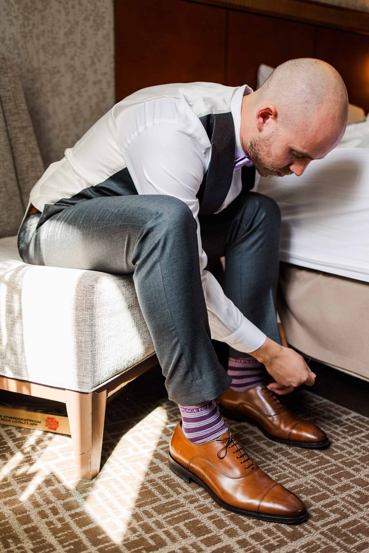 Groom in a Tacoma hotel room, putting on his brown loafers and purple socks
