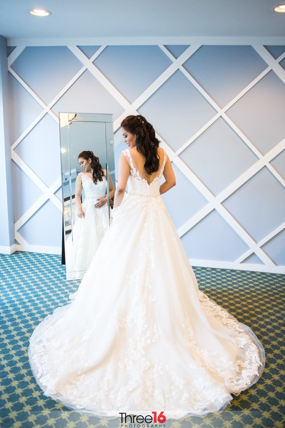 Bride posing in front of mirror with her gown train in full bloom