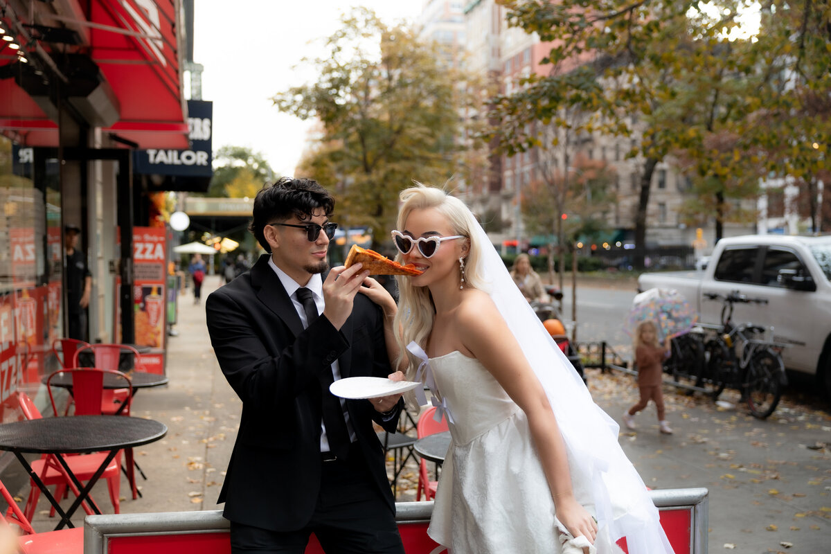 Couple sitting together at a pizza shop in NYC after their elopement, sharing a fun moment with pizza.