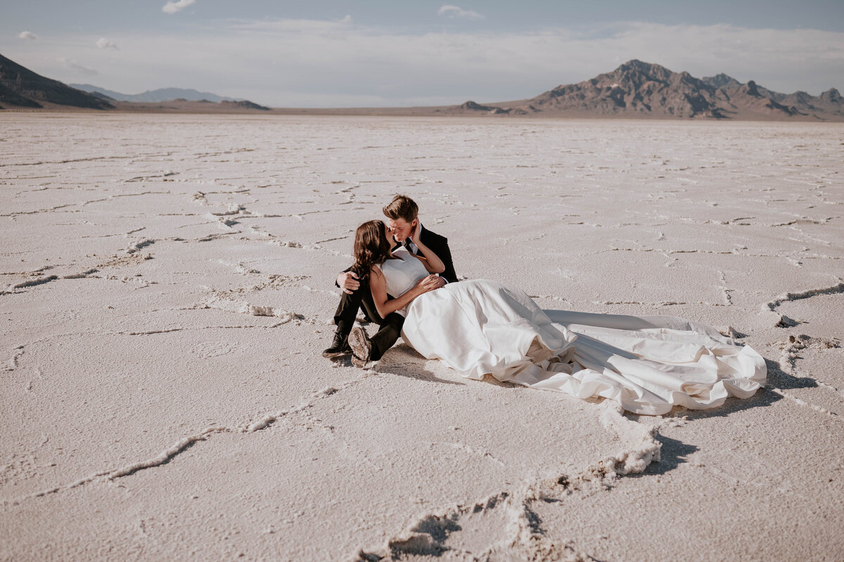 Newlywed couple sit on sand during their destination wedding