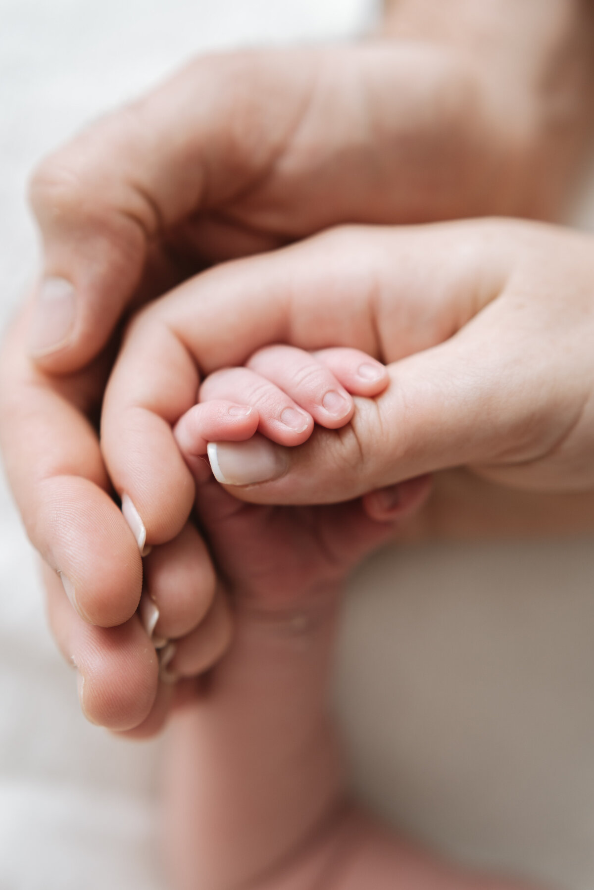 Mother and father holding their newborns hand