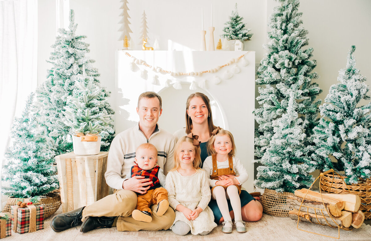 colorado wedding photographers family sitting together in a winter wonderland backdrop for their denver family photos