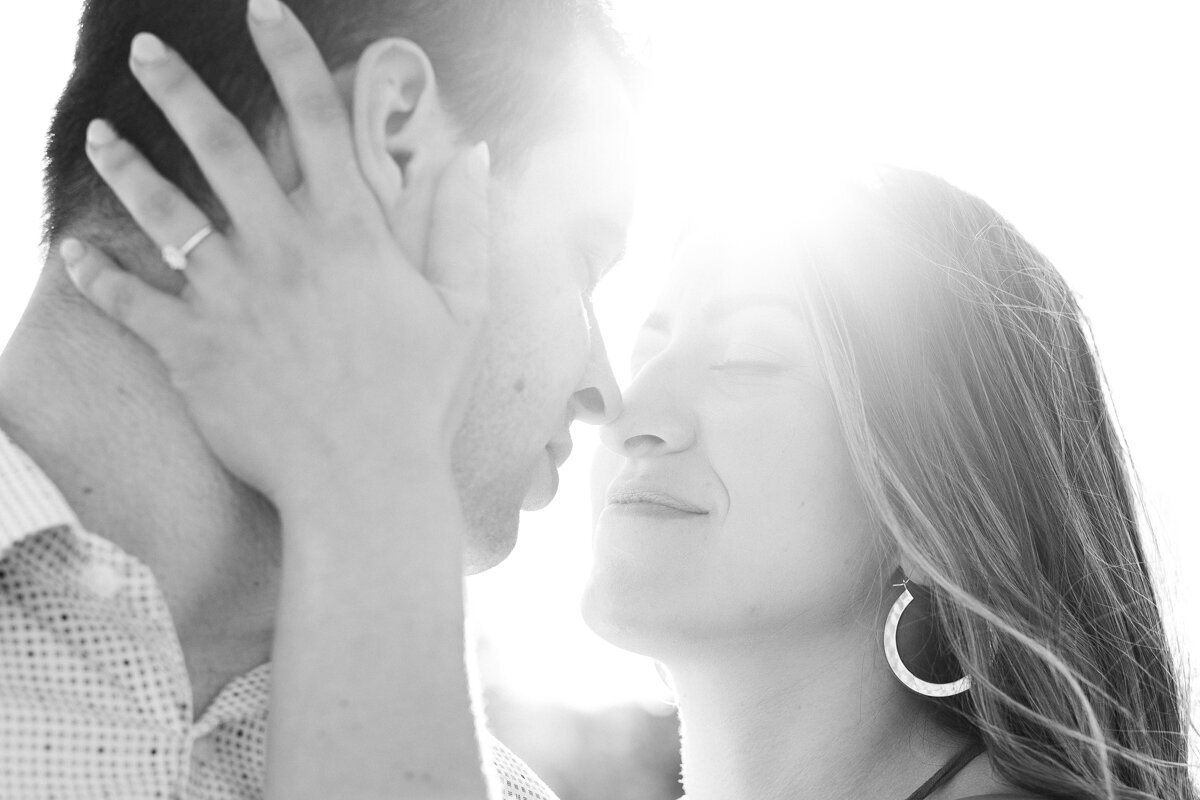 Intimate black and white  image of couple almost kissing with sun-flair between their heads in Albany, NY