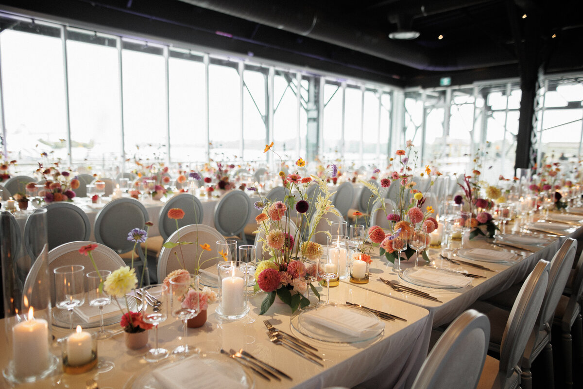 Rows of tables topped with colourful floral centrepieces decorate the Science Centre for a wedding reception.