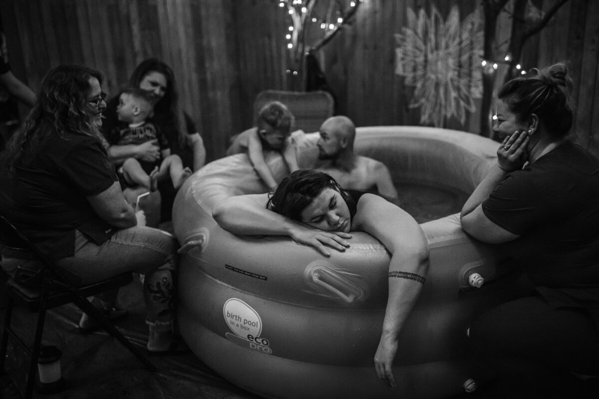 woman in birth pool surrounded by family and midwives