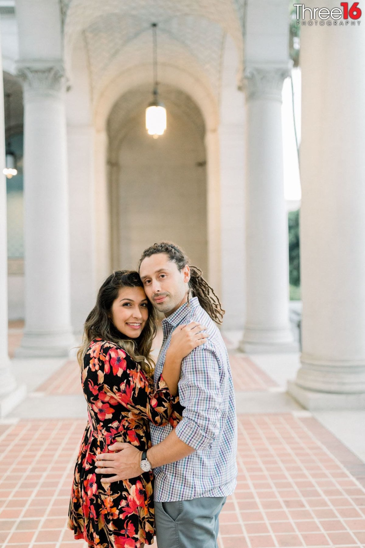 Engaged couple embrace one another as they pose for engagement photos