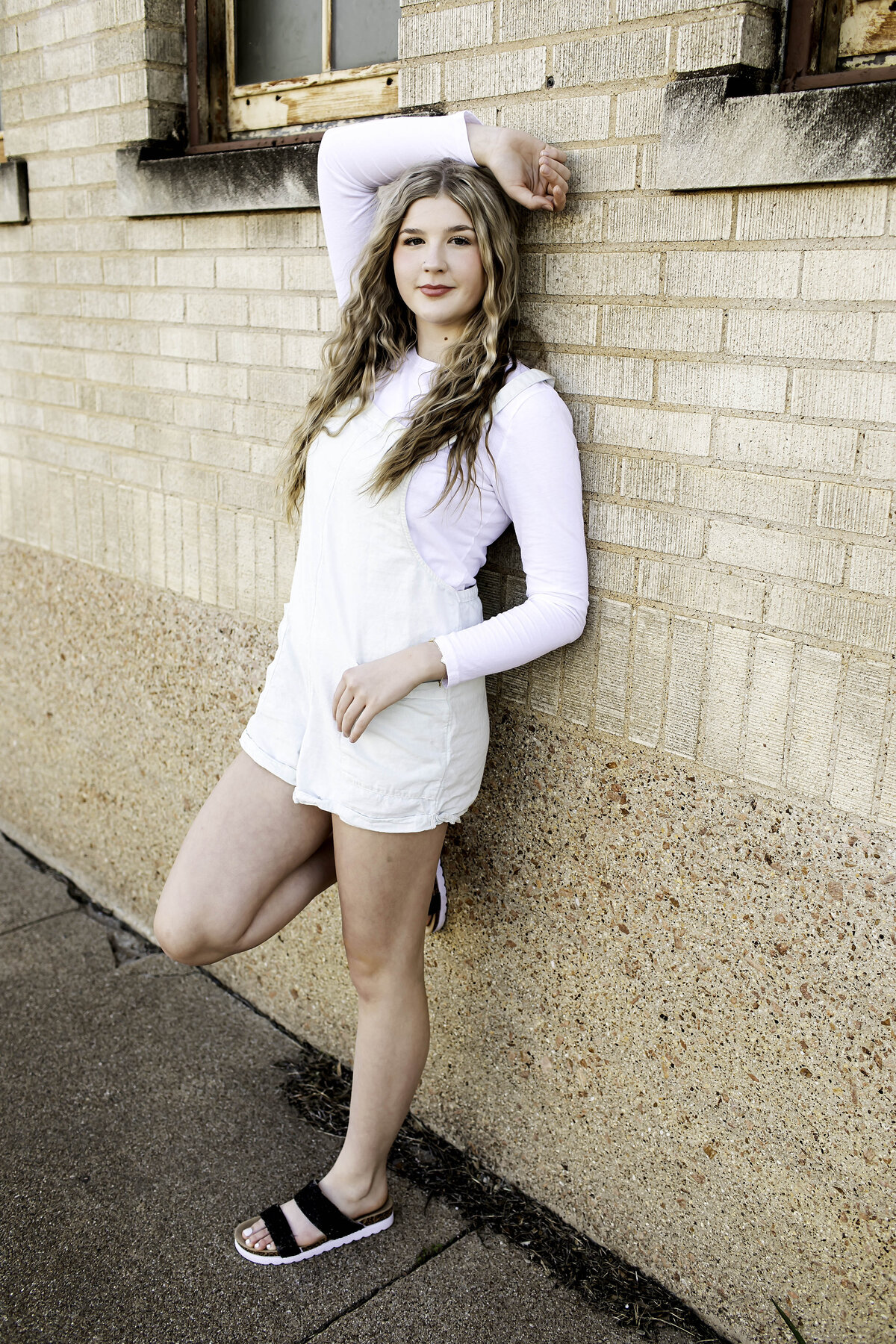 A senior smiles softly, standing with arms gently crossed, embracing a moment of calm
