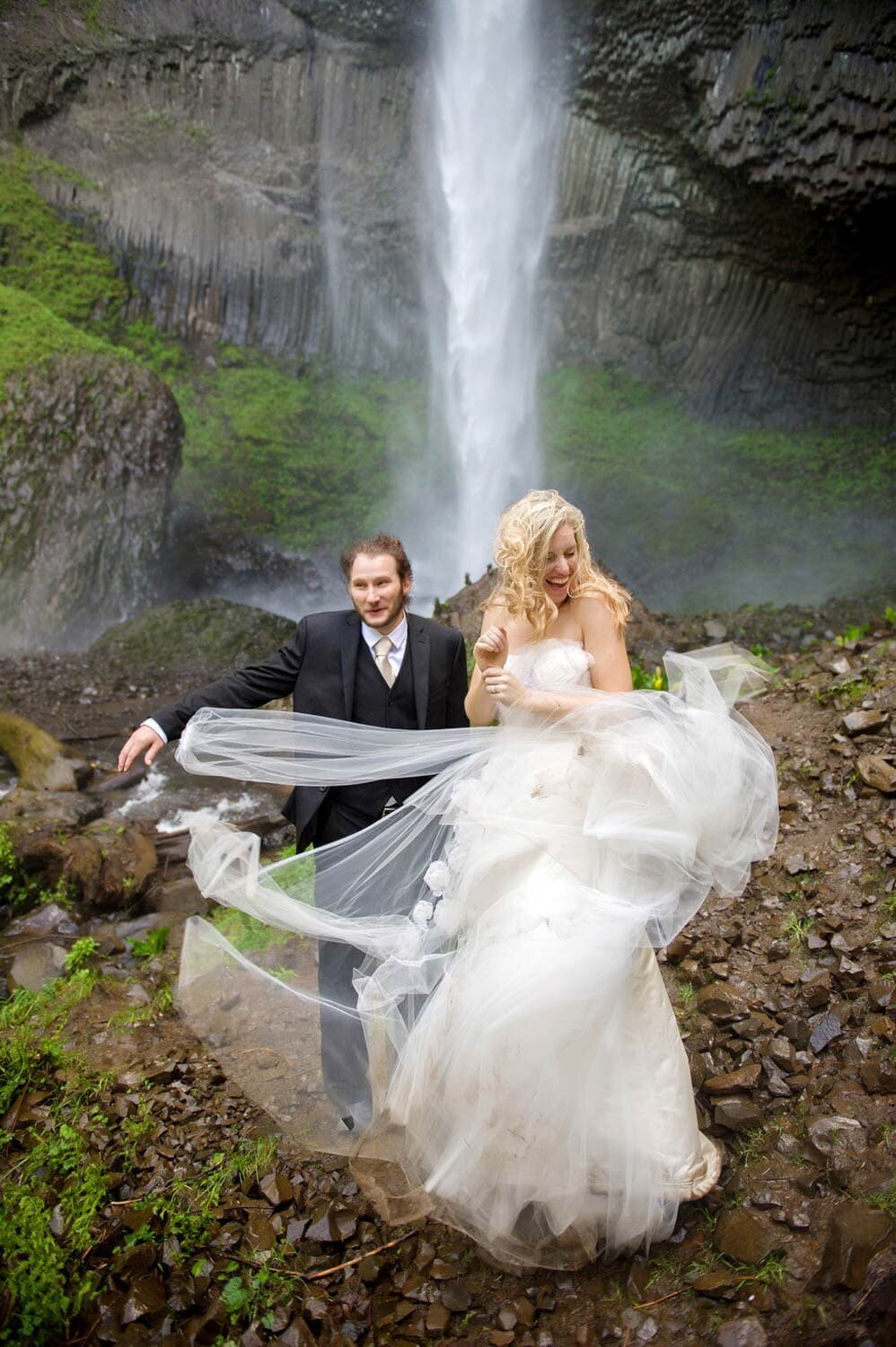 a bride's wedding dress flies in the wind as though she's about to fly away