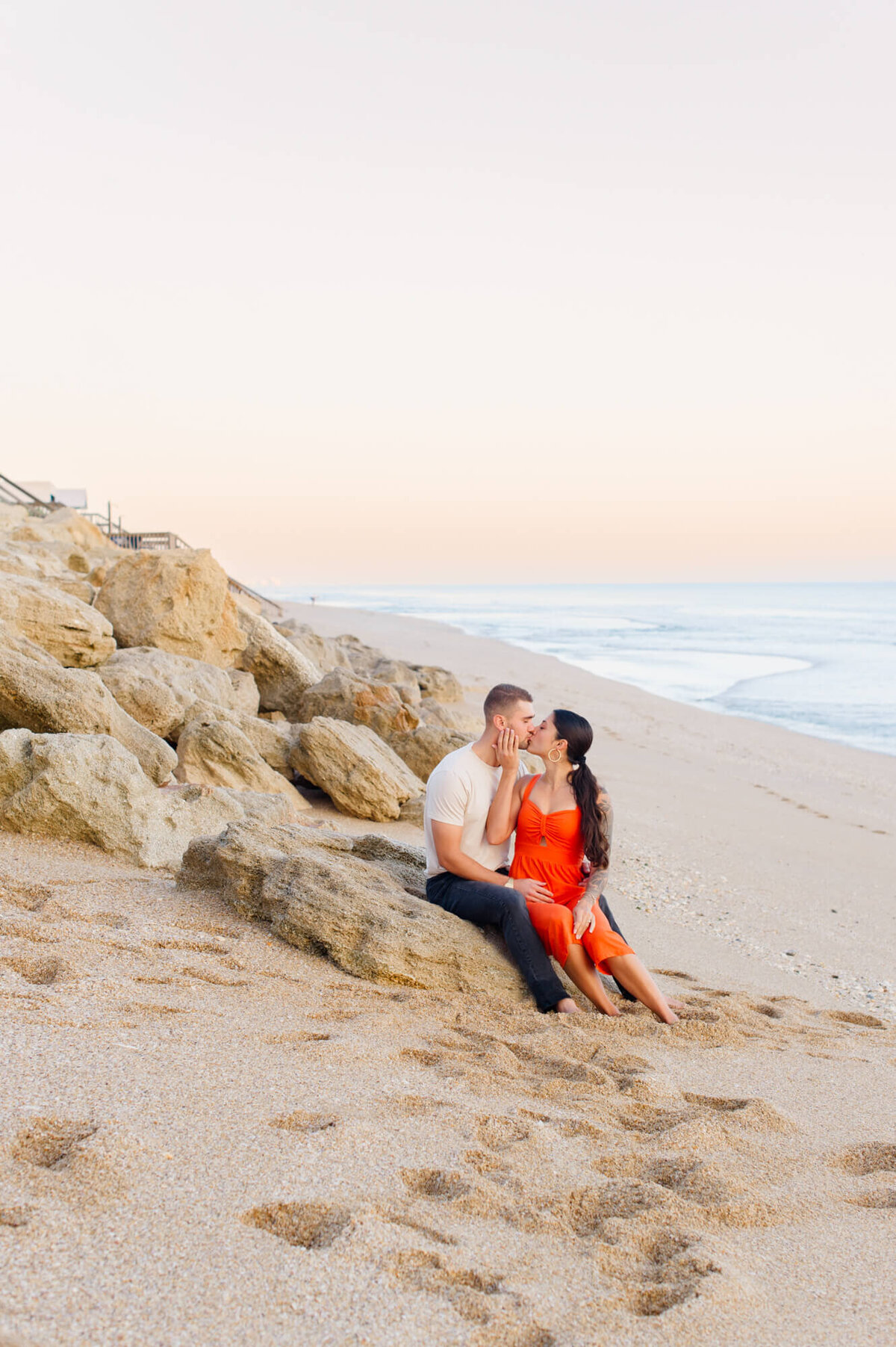 Couple kissing on rocks after their proposal at sunrise with Orlando photographer.