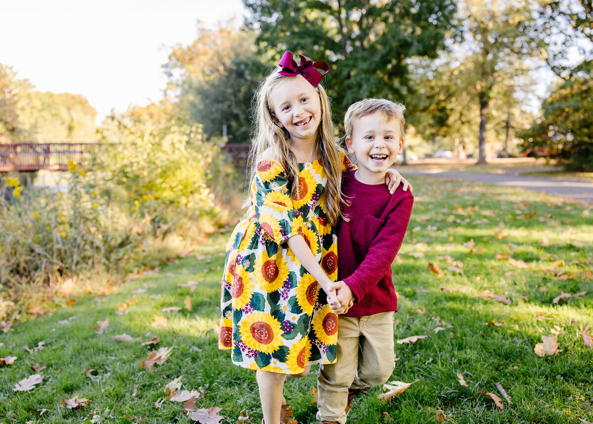 Lifestyle photo of siblings smiling and dancing at a Union County, New Jersey park in the fall.