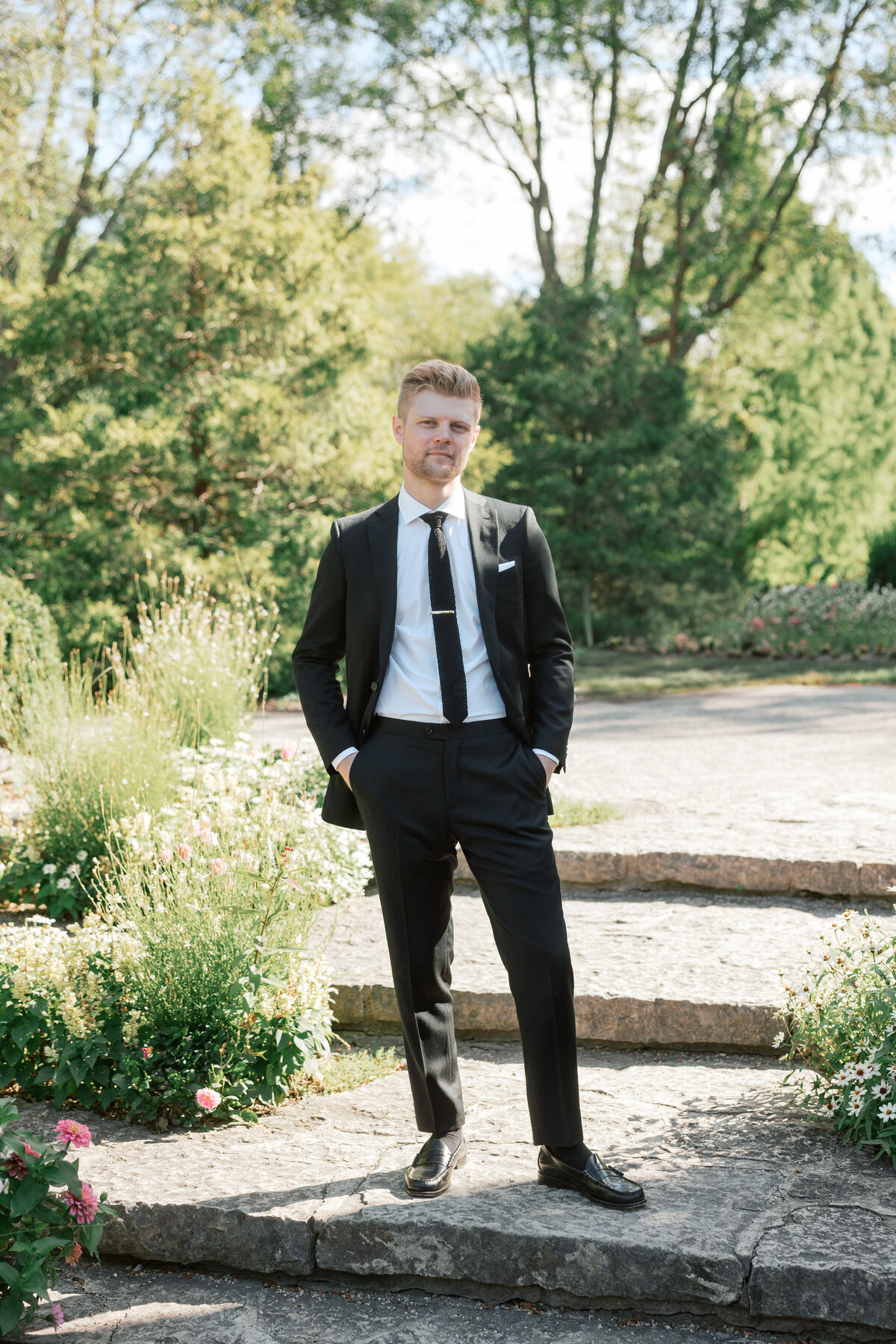 Groom poses solo in Dayton garden wedding, styled in classic black suit, Philadelphia photographer image.