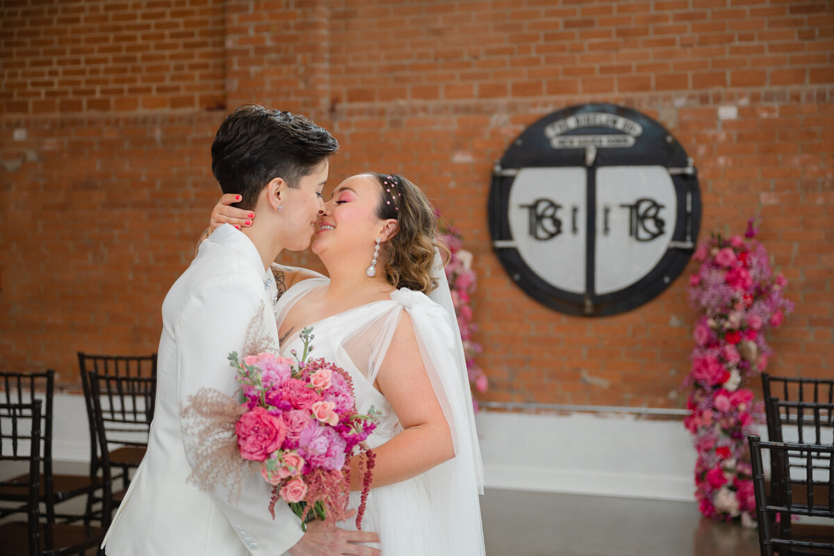 Two brides smiling about to kiss