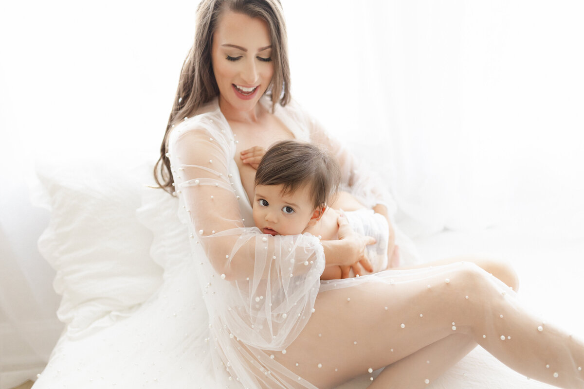 Luxury motherhood moment in Tampa studio: mother gently nursing baby in soft, editorial light