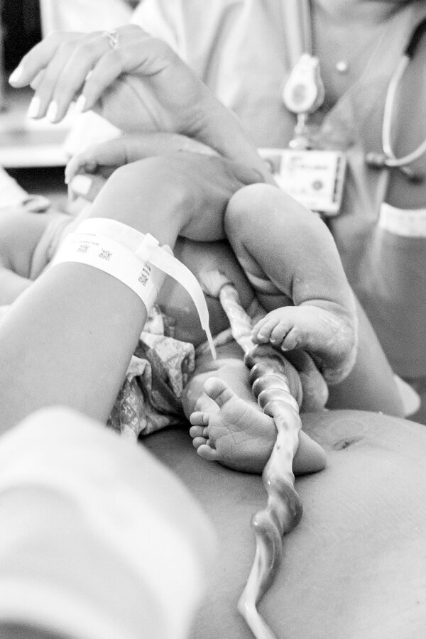 Newborn birth of baby's feet with umbilical cord.