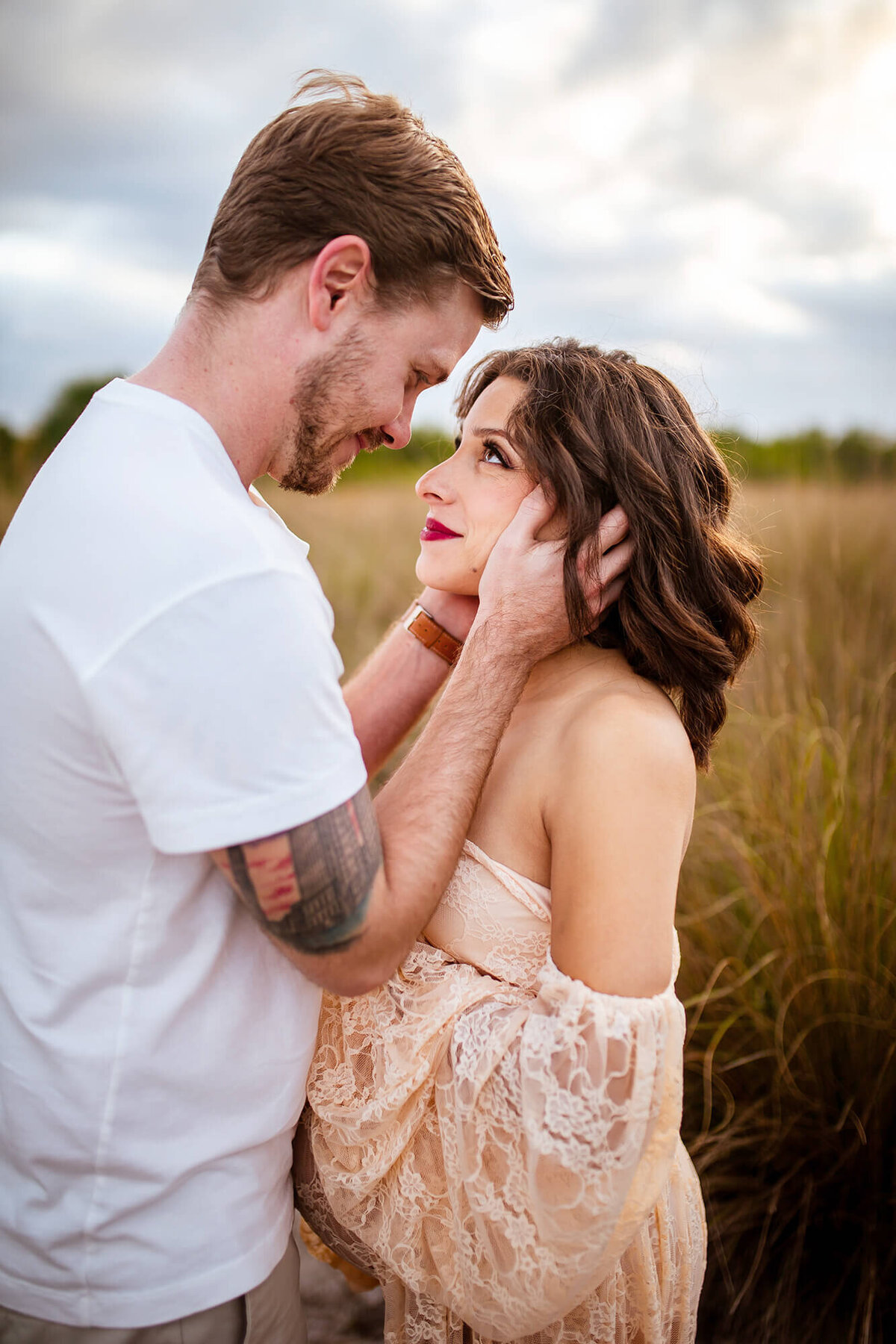 Stunning golden light maternity session. Intimate moment with husband about to kiss wife her looking at him and smiling. Captured at Cypress Point Park in Tampa, FL