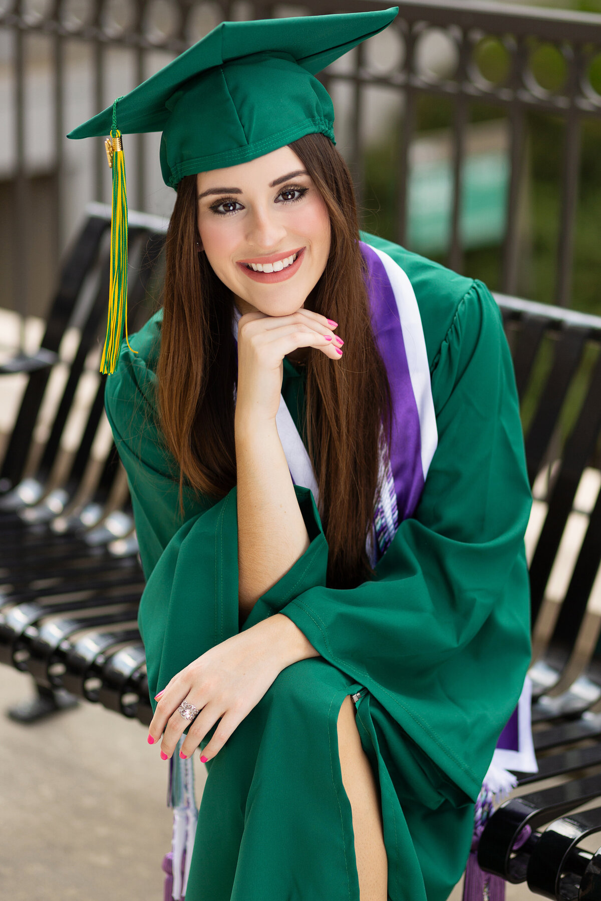 Graduating nursing student sitting on a bench.