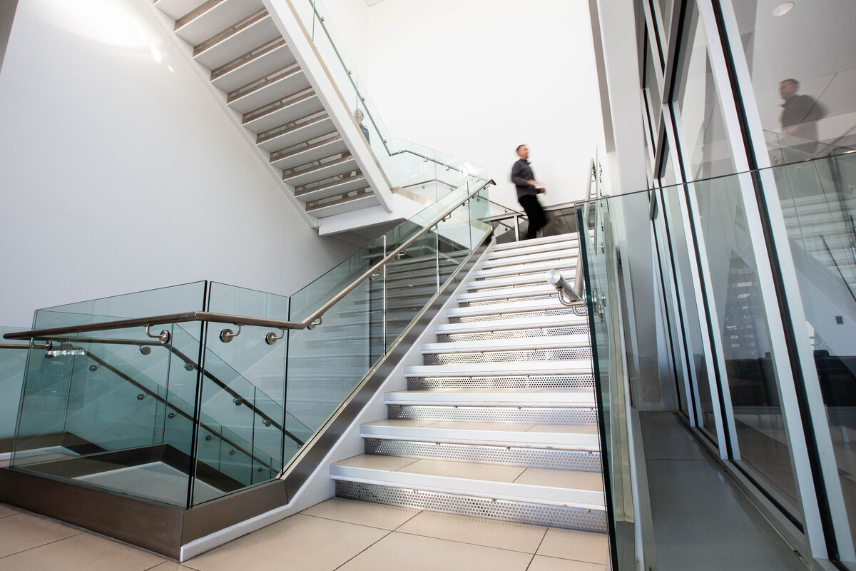 Stairwell with glass railings and figure in motion