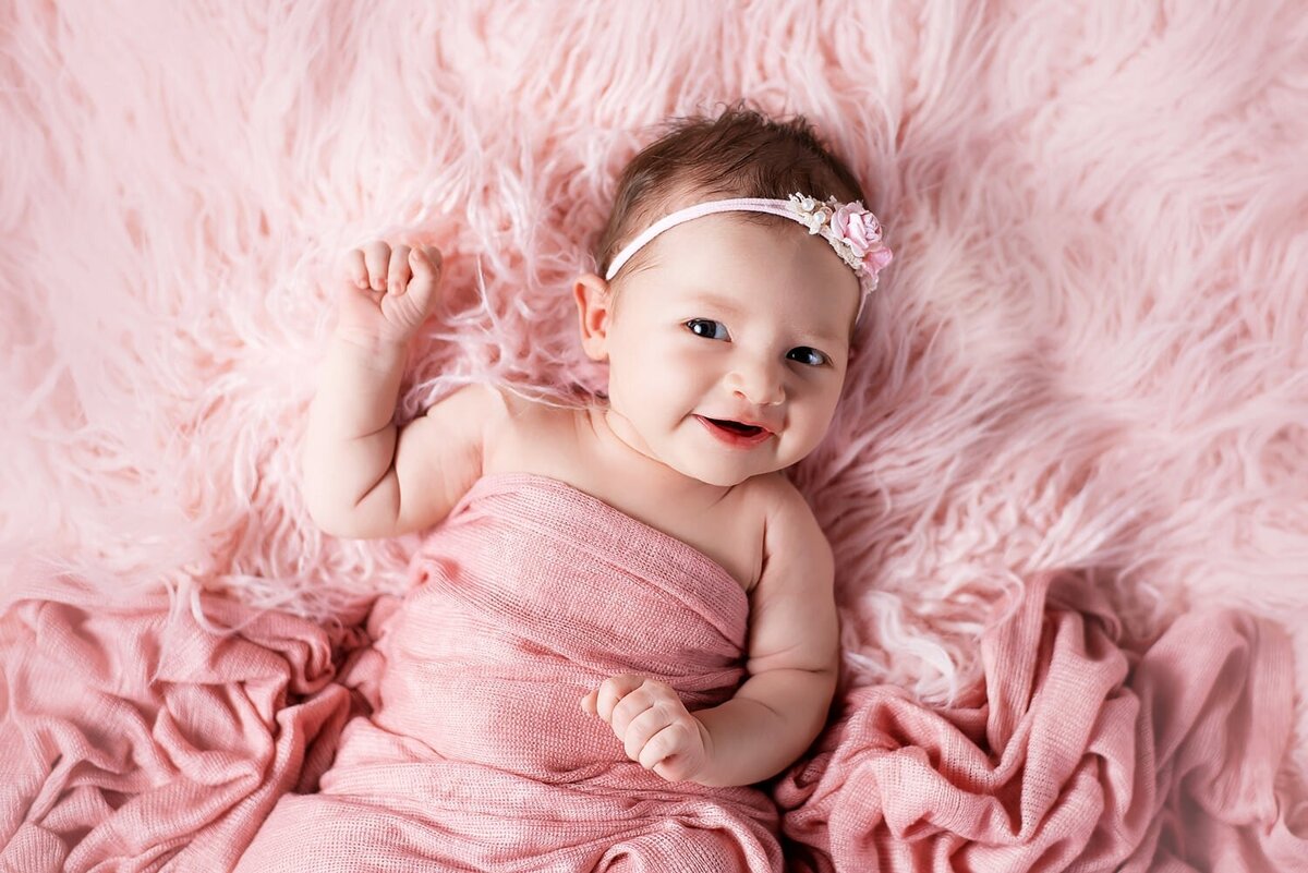 Smiling newborn baby girl in pink wrap