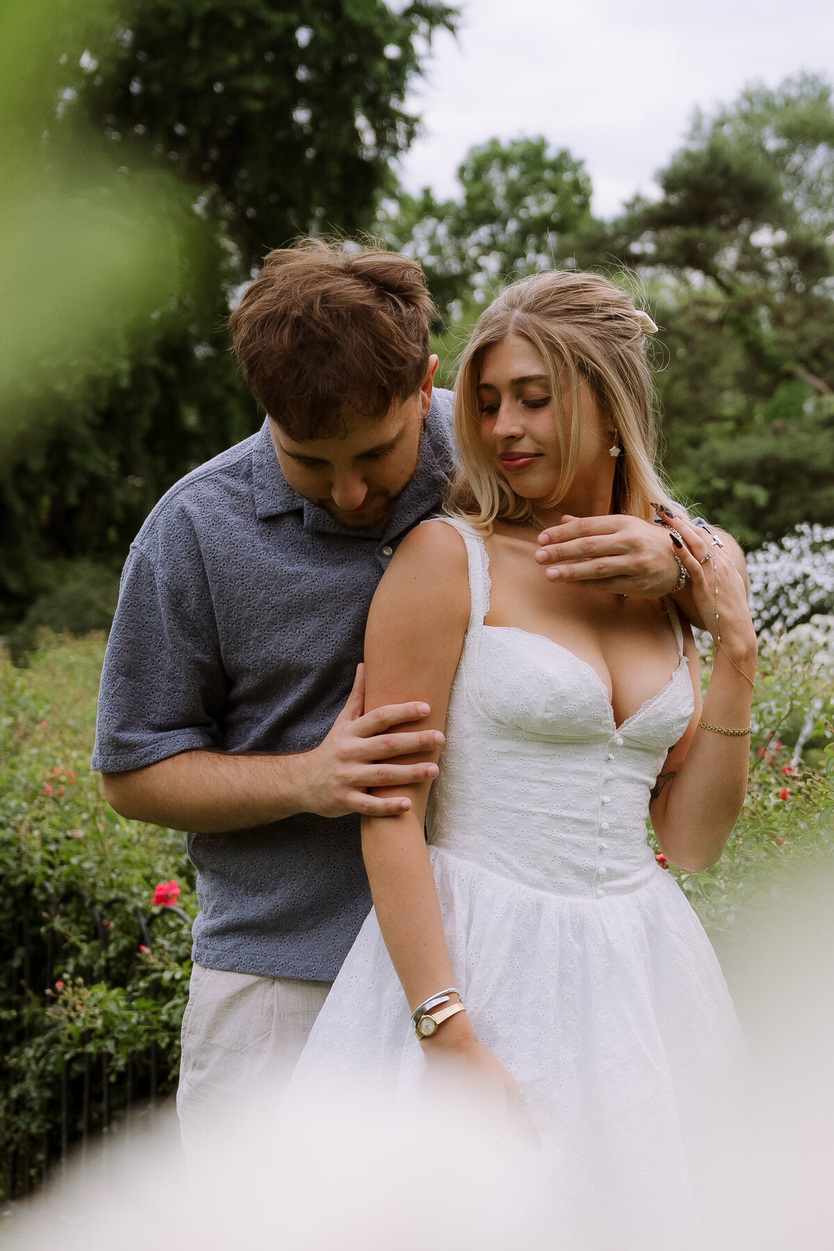 happy couple posing in front of rose bushes