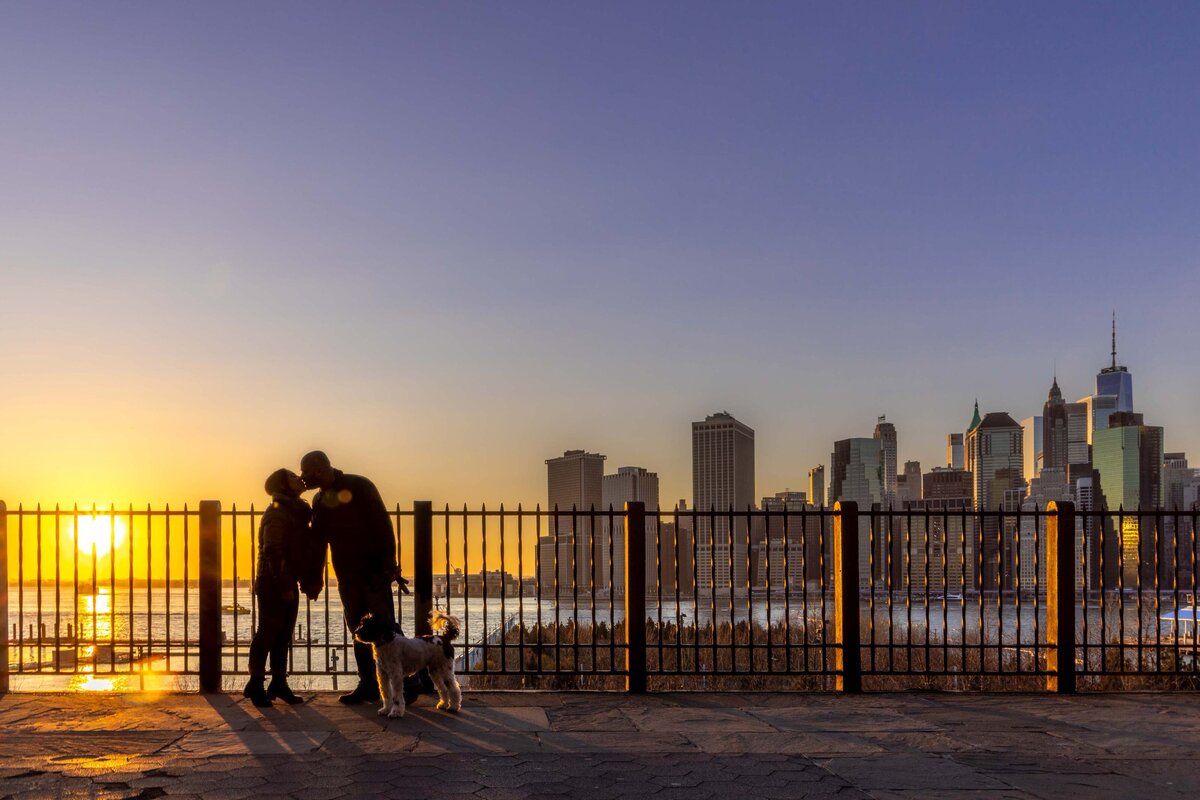 A couple kissing as the sun sets behind them.
