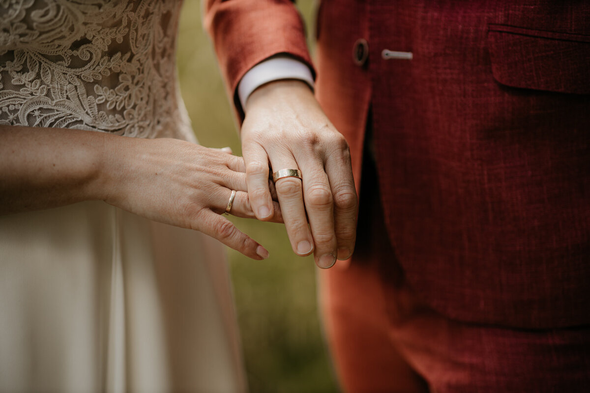 lose-up van het bruidspaar dat elkaar de ringen omdoet tijdens een romantisch moment in zachte belichting.