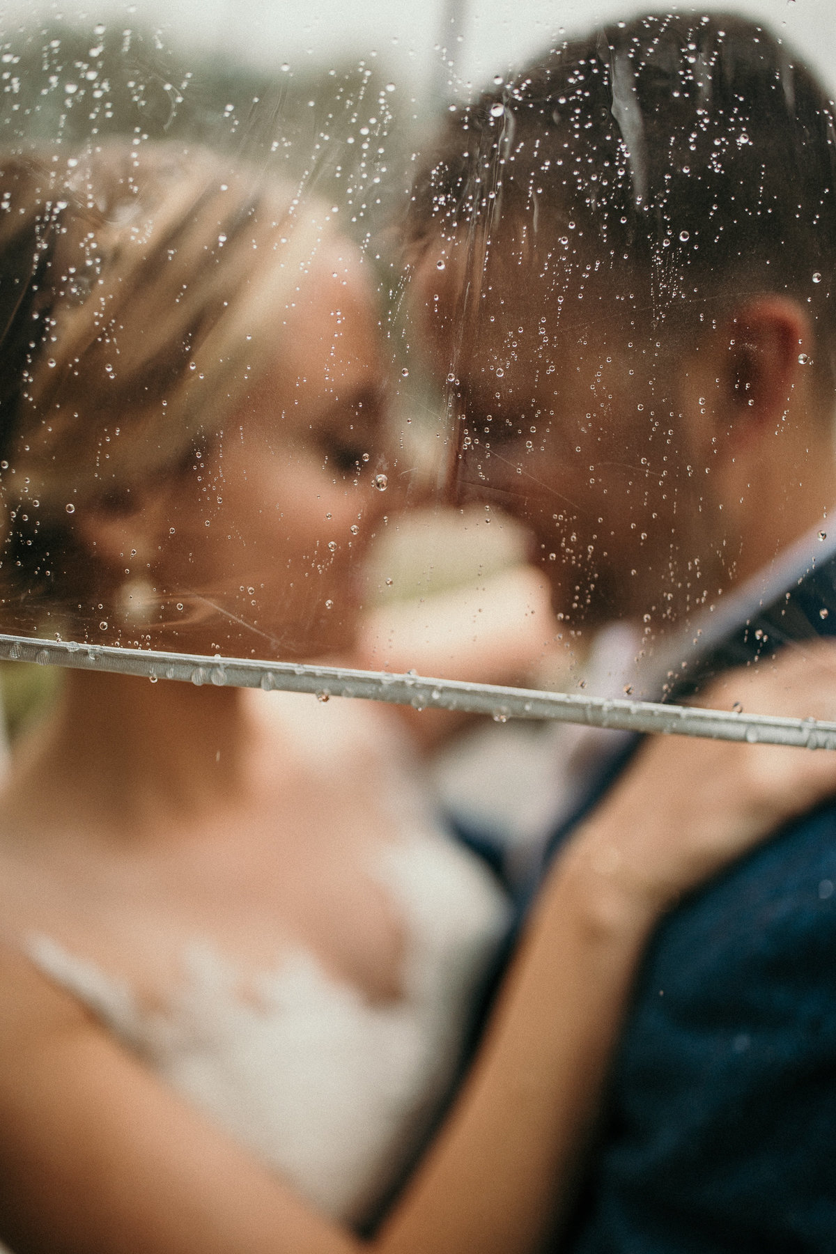 Bride and groom under umbrella rainy wedding