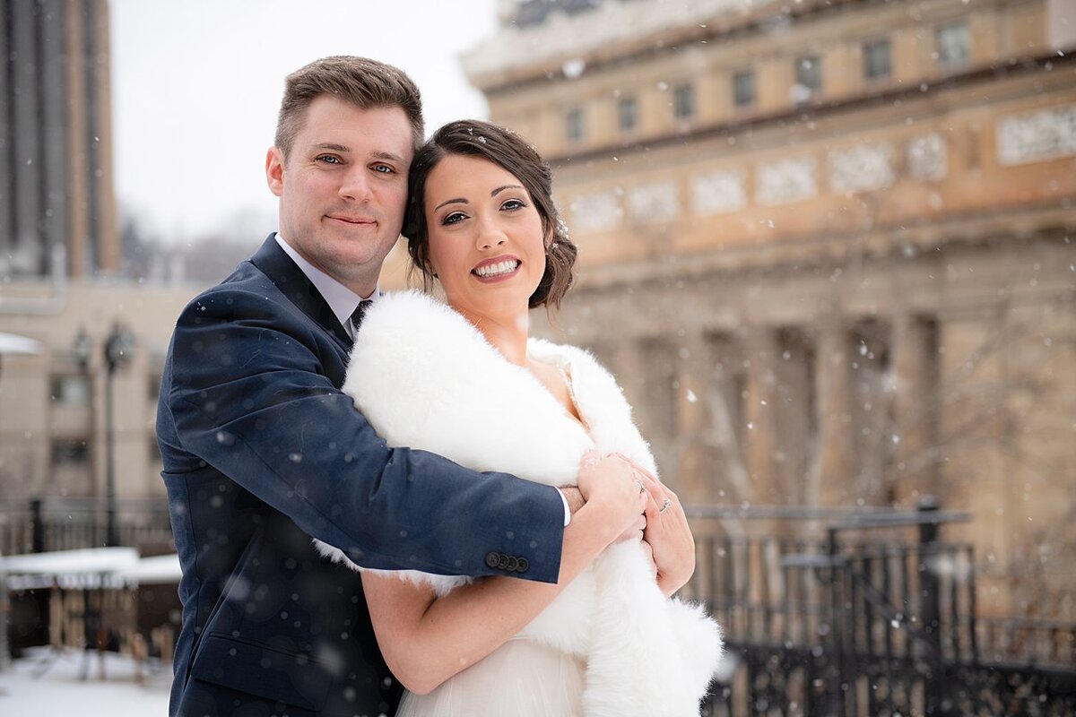 Bride with fur wrap and Groom on snowy rooftop at University Club in Pittsburgh, PA
