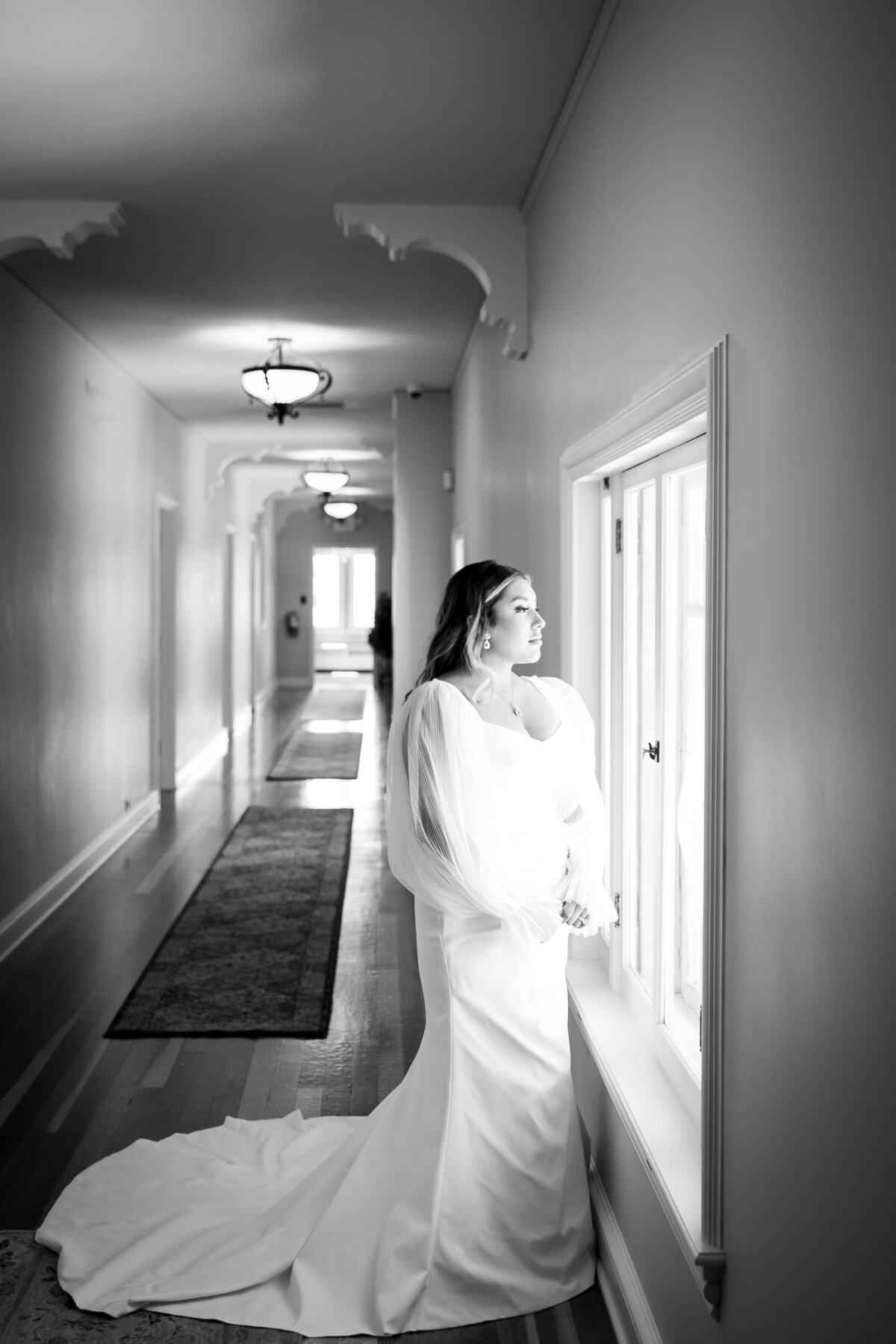 An elegant bride stares out the window on her wedding day.