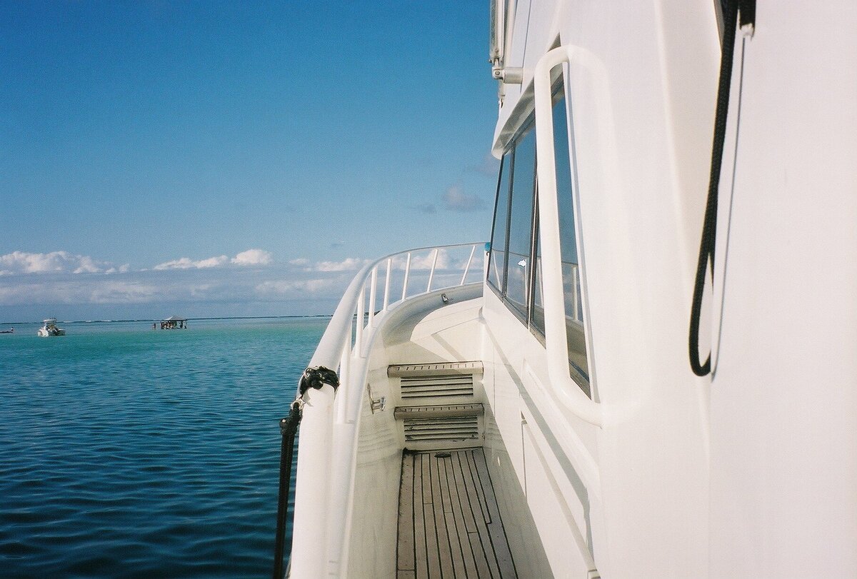 Yacht on open water captured on film by Kate Winters Photography, showcasing the vast expanse of the ocean and the elegance of the vessel in an authentic, documentary style.