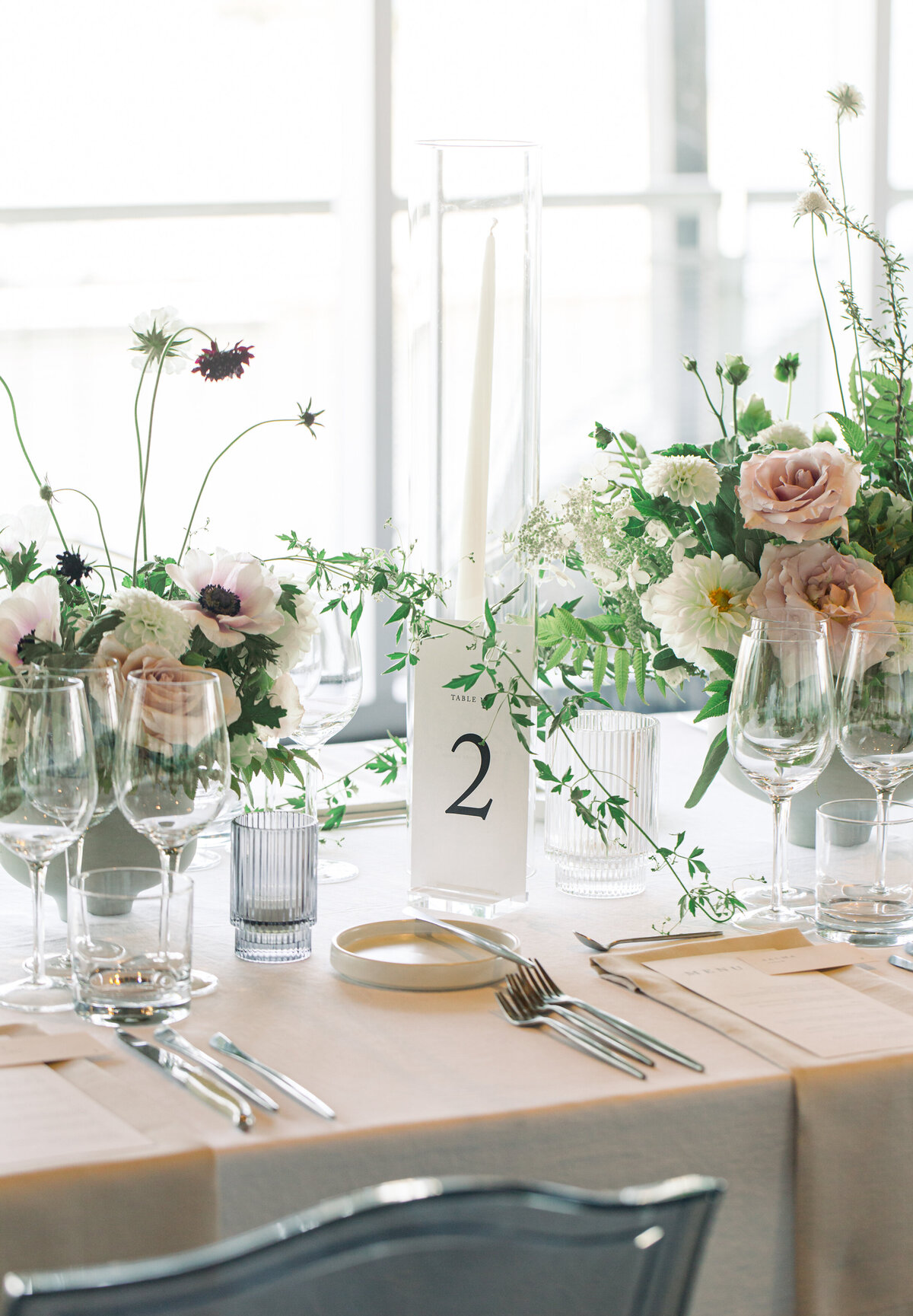 Centrepieces of lush, pastel garden flowers and greenery at a Science Centre wedding reception.