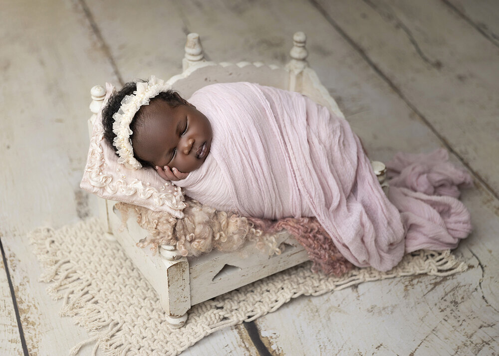 NEWBORN_BABY_BLACKBABYGIRLINABABYBEDWRAPPED
